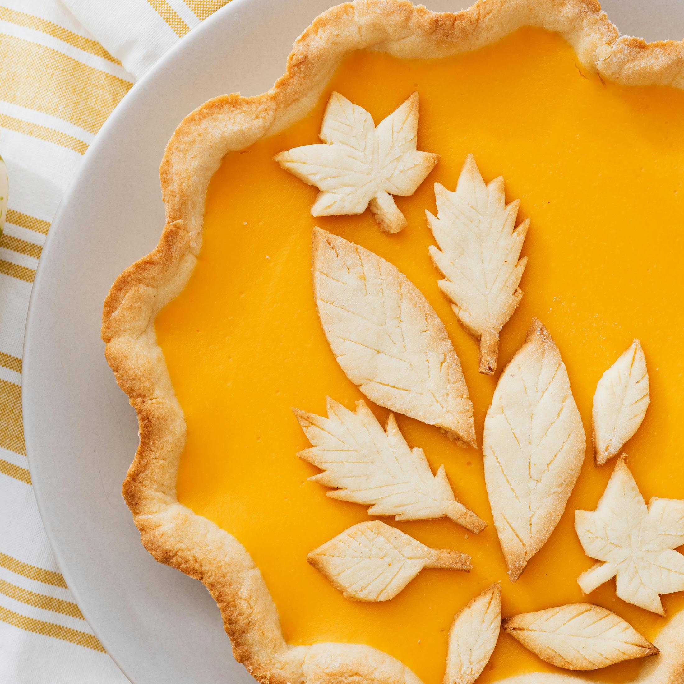 Pie-top-shot-2000-01 A close-up of a pie with a golden filling and decorative leaf-shaped crust on top.