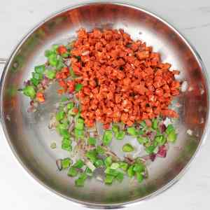 Chopped chorizo, green and red bell peppers, and onions in a skillet.