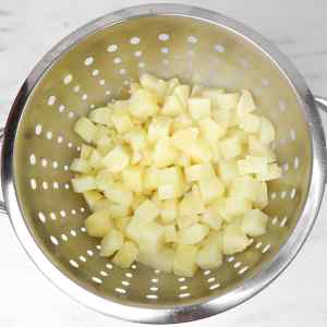 Chopped potatoes in a colander, ready for cooking in a potato and chorizo hash.