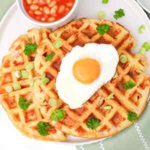 Gaufres salées garnies d'un œuf au plat, d'oignons verts et de persil, servies avec des haricots blancs à la sauce tomate.
