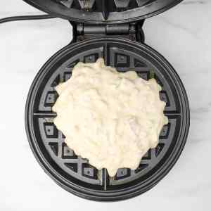 Pâte à gaufres salées dans un gaufrier, prête à être cuite.