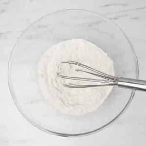 Un bol en verre rempli de farine et un fouet posé à l'intérieur.