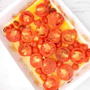 Tomates rôties dans un plat allant au four, brillantes d'huile d'olive et assaisonnées d'herbes.