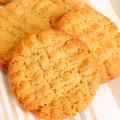 Close-up of golden brown peanut butter cookies on a striped cloth.