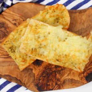 Two pieces of cheesy garlic bread on a wooden serving board.