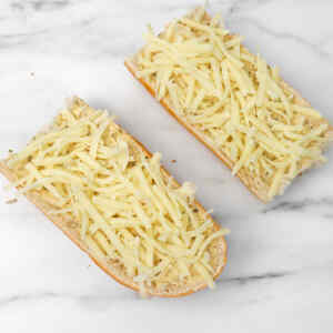 Two pieces of bread topped with shredded cheese ready for air frying.