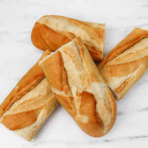 Four pieces of freshly baked bread with a golden crust on a marble surface.