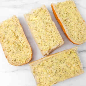 Mit Knoblauchbutter und Kräutern bestrichene Brotscheiben, bereit zum Frittieren in der Heißluftfritteuse.