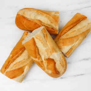 Vier Stücke goldbraunes Knoblauchbrot auf einer Marmoroberfläche.