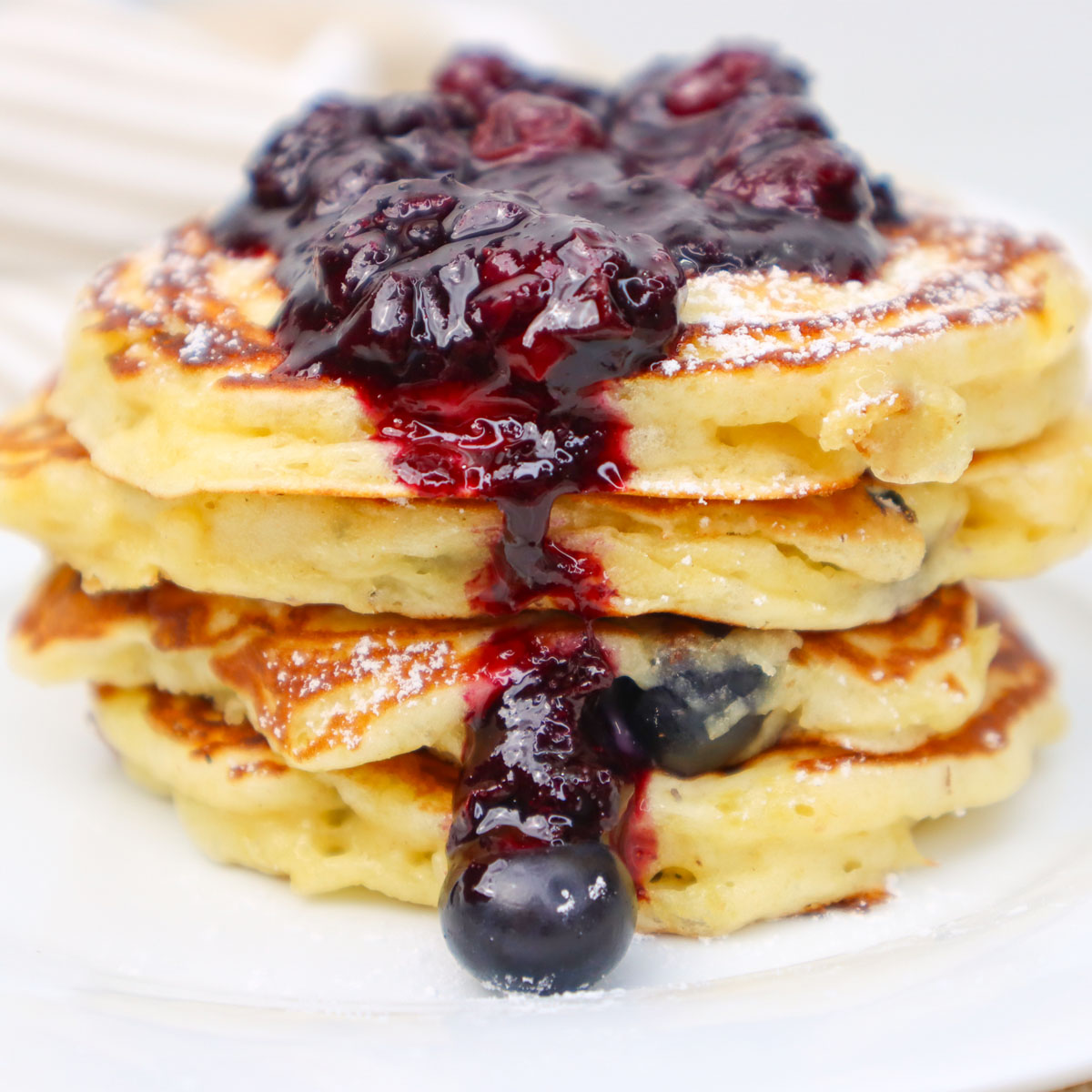 Pancake Buttermilk Blueberry Setumpuk panekuk buttermilk blueberry yang lembut, diberi saus beri dan blueberry segar.