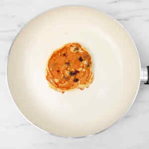 Une crêpe au babeurre et aux myrtilles qui cuit dans une poêle.
