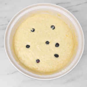 Bol de pâte à crêpes garni de myrtilles, prêt à être cuit.