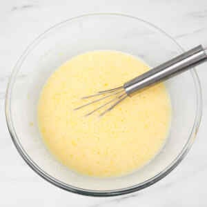 Un bol de pâte à crêpes au babeurre, avec un fouet à l'intérieur.