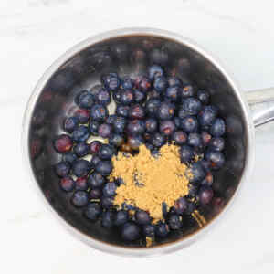 Fresh blueberries and brown sugar in a saucepan, ready to be cooked into compote.