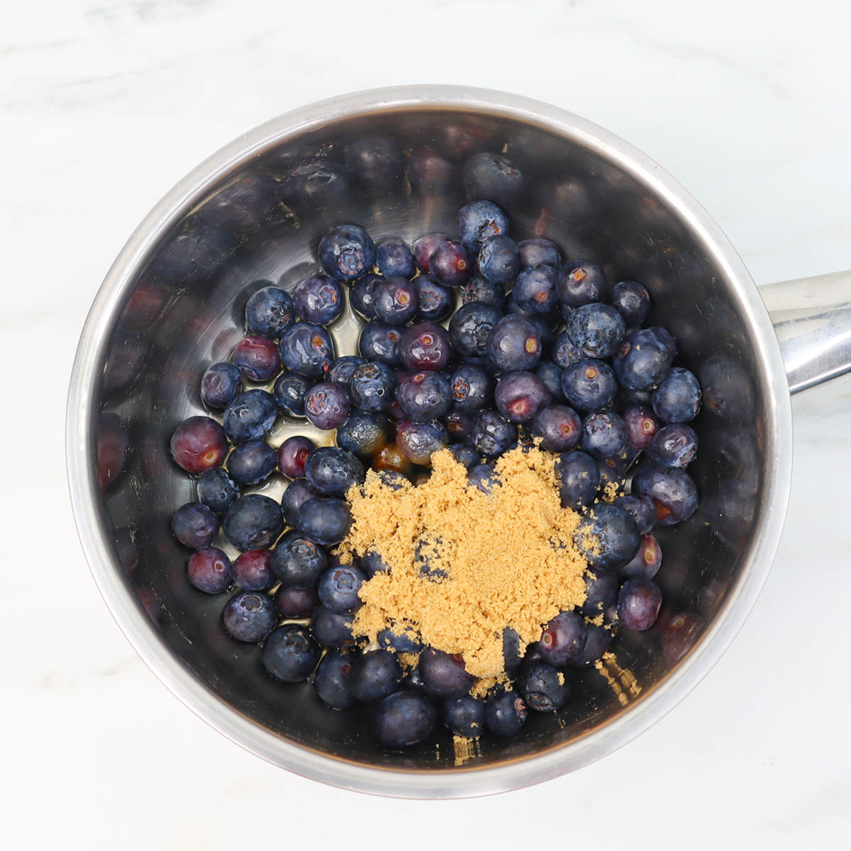 Blueberry Compote Fresh blueberries and brown sugar in a saucepan, ready to be cooked into compote.