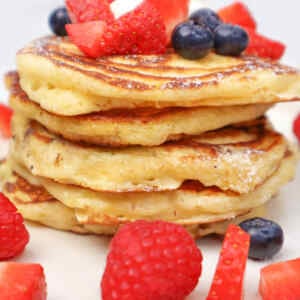 Pilha de panquecas fofinhas de buttermilk cobertas com morangos, mirtilos e framboesas.