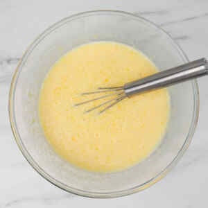 Uma tigela com massa de panqueca de leitelho e um batedor de arame dentro.