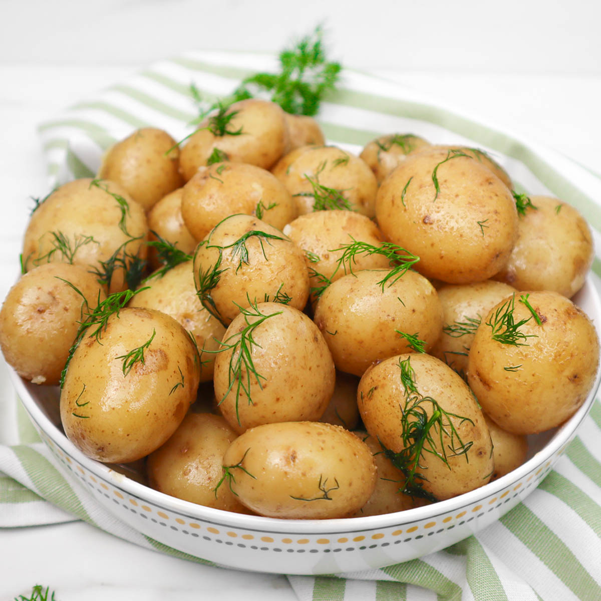 Buttery Boiled New Potatoes A bowl of buttery boiled new potatoes garnished with fresh dill.