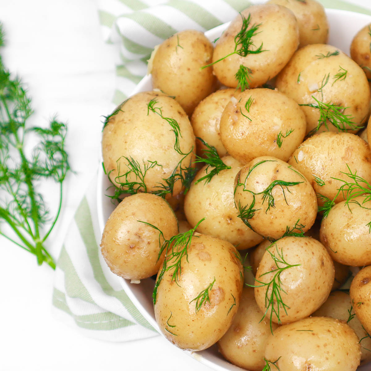 Buttery Boiled New Potatoes A bowl of buttery boiled new potatoes garnished with fresh dill.