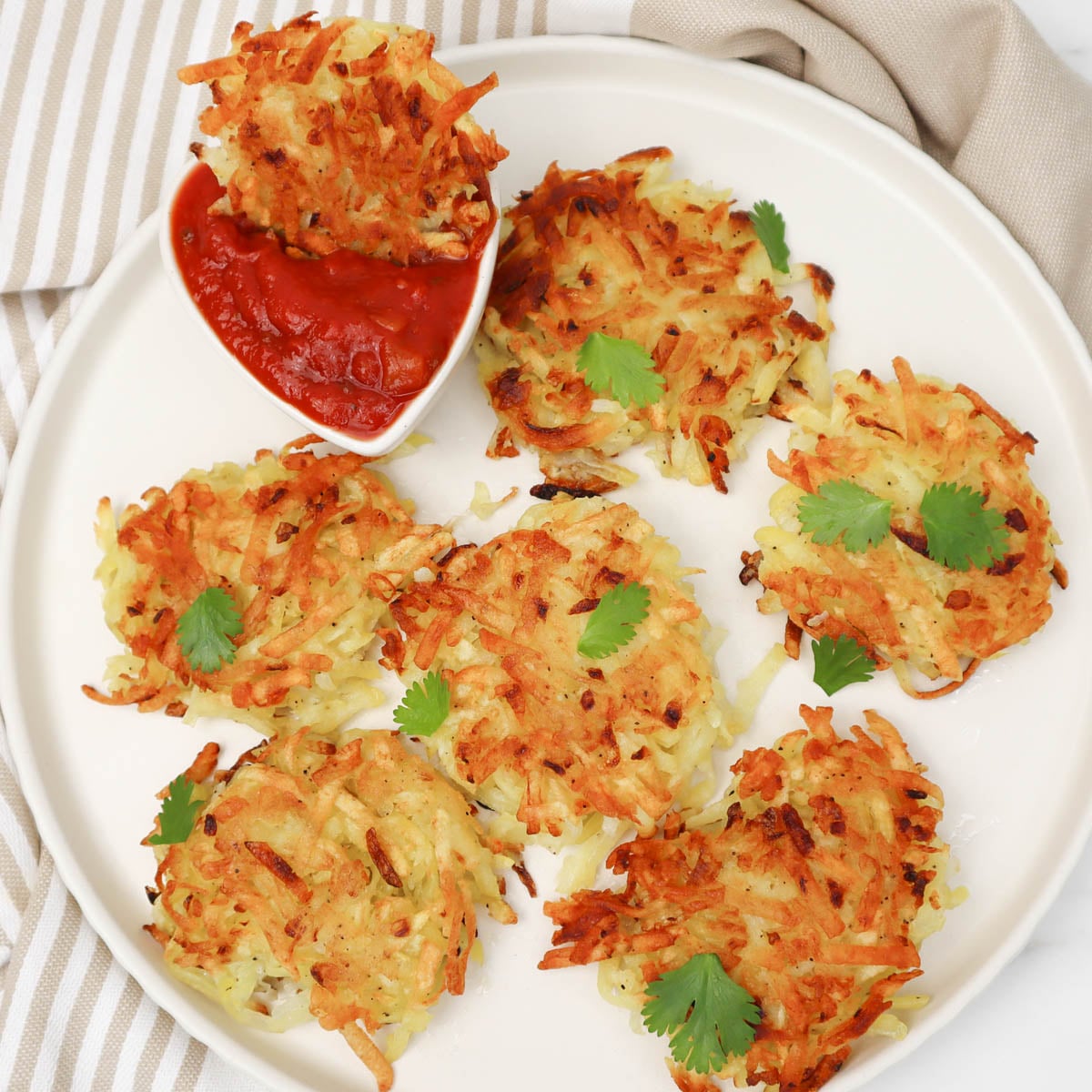 Hash Browns Crispy hash browns served with a side of dipping sauce and garnished with fresh cilantro.