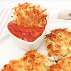 Crispy hash browns served with a side of dipping sauce.