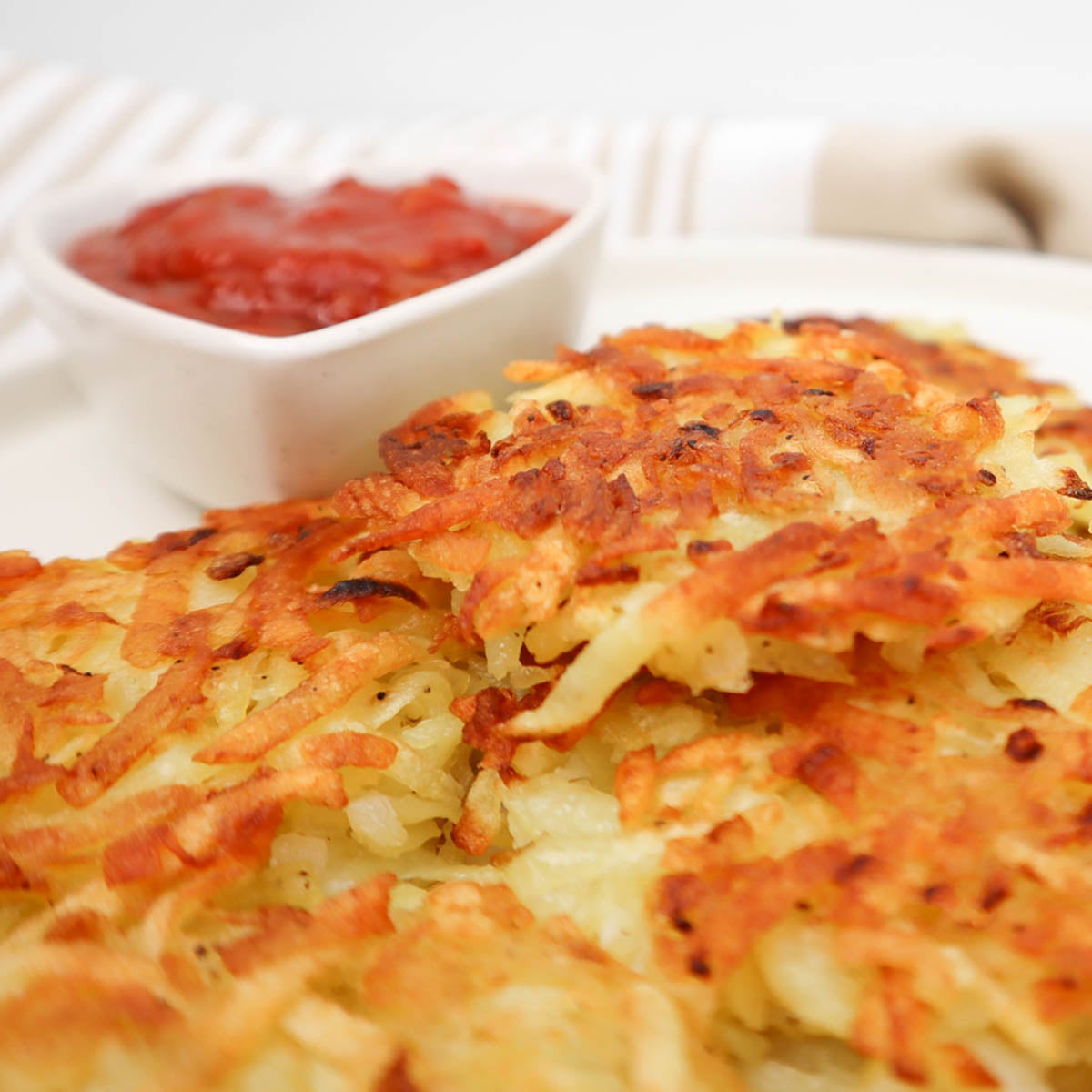 Hash Browns Crispy golden hash browns served with a small bowl of ketchup.