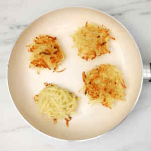 Golden-brown hash browns cooking in a skillet.