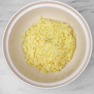 Shredded potatoes in a bowl, ready for making hash browns.