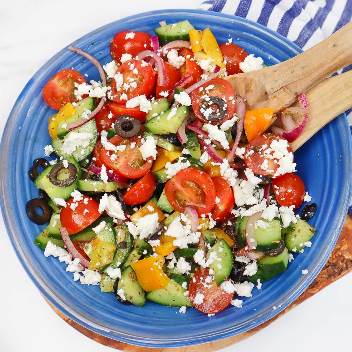 Mediterranean Salad A vibrant Mediterranean salad with tomatoes, cucumbers, olives, and feta cheese in a blue bowl.