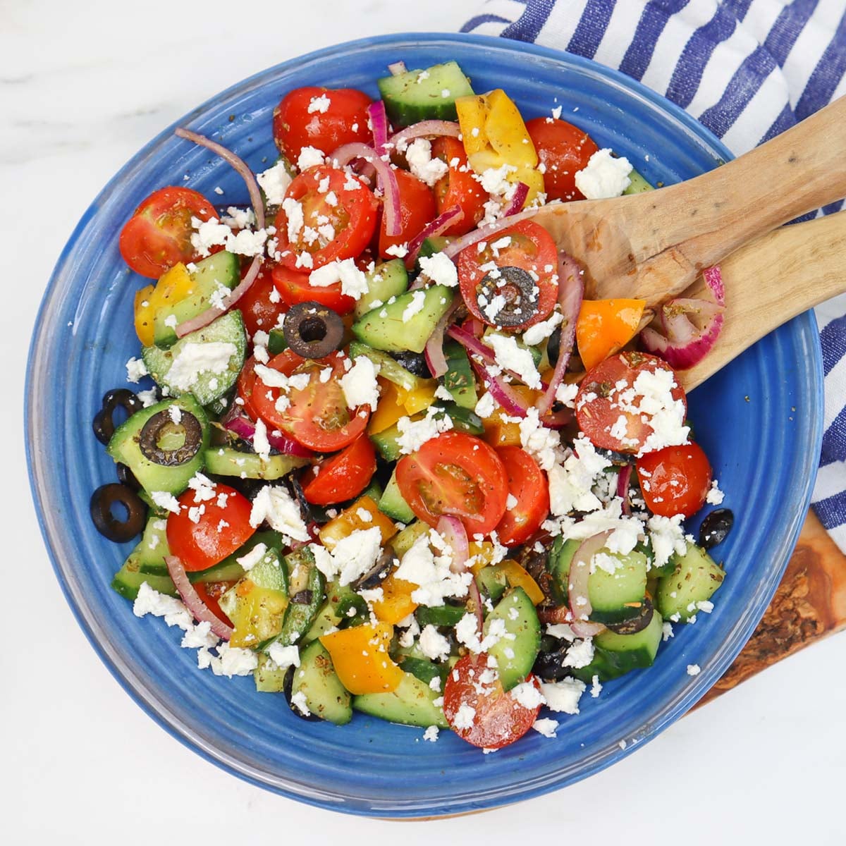 Mediterranean Salad A colorful Mediterranean salad with tomatoes, cucumbers, peppers, olives, and feta cheese in a blue bowl.