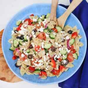 Mediterranean pasta salad with farfalle, cherry tomatoes, cucumber, black olives, and crumbled feta.