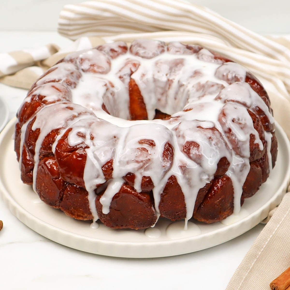 Pull Apart Monkey Bread A close-up of pull-apart monkey bread drizzled with icing on a white plate.