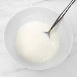 Semangkuk krim putih lembut dengan sendok, untuk kue pai stroberi.
