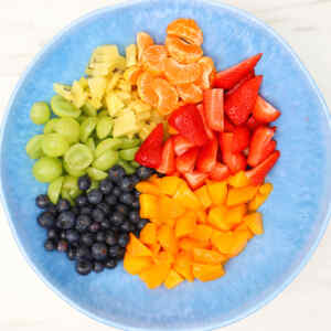 A colorful summer fruit salad with grapes, strawberries, blueberries, pineapple, mandarin oranges, and mango.