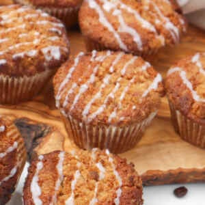 Freshly baked coffee cake muffins drizzled with icing on a wooden surface.