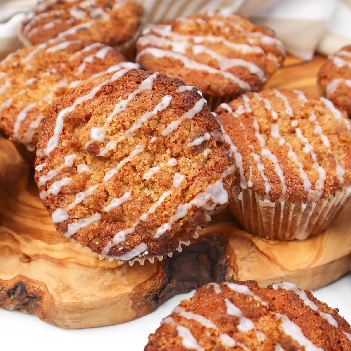 Coffee Cake Breakfast Muffins Freshly baked coffee cake breakfast muffins drizzled with icing on a wooden surface.