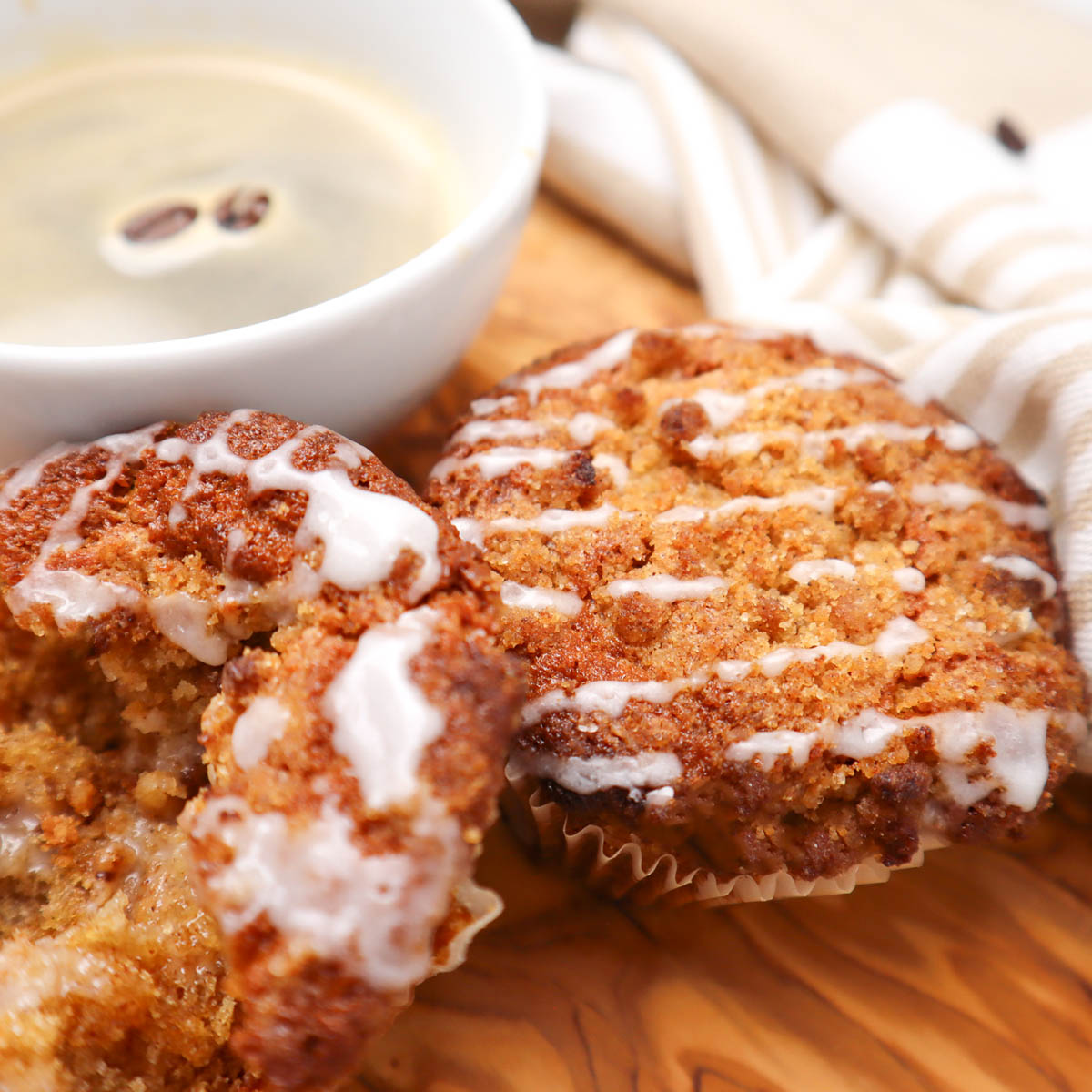 Coffee Cake Breakfast Muffins Two coffee cake breakfast muffins drizzled with icing next to a cup of coffee.