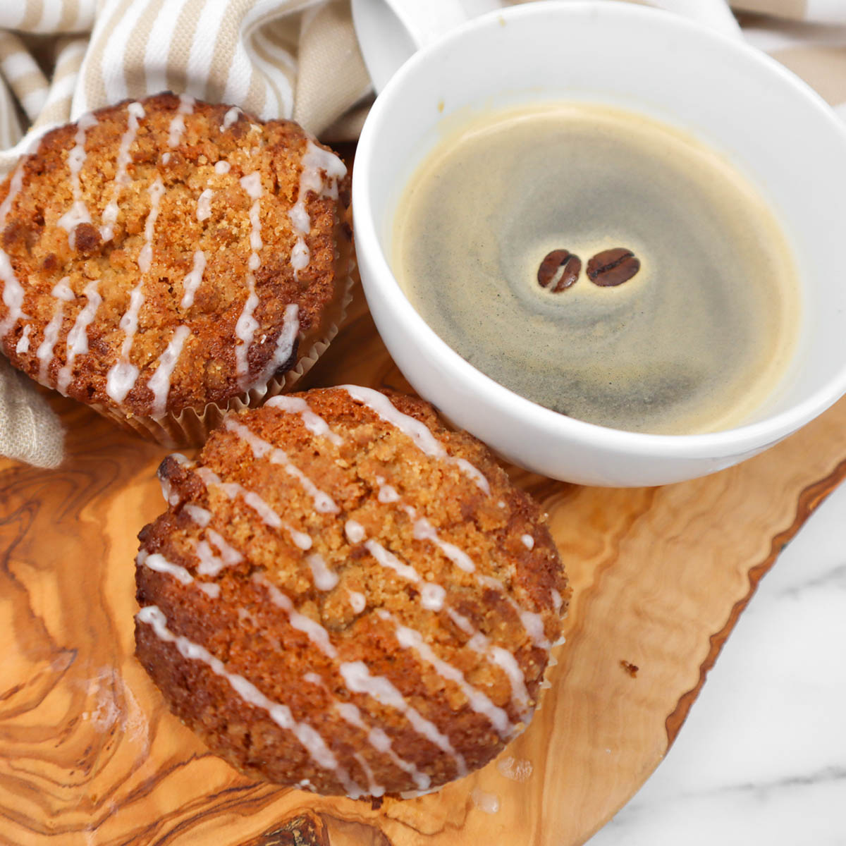 Coffee Cake Breakfast Muffins Two coffee cake breakfast muffins drizzled with icing next to a cup of coffee.