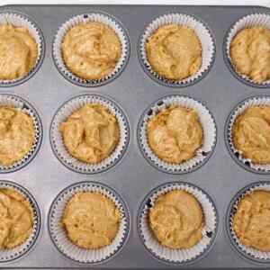 Muffin tin filled with unbaked coffee cake breakfast muffin batter.