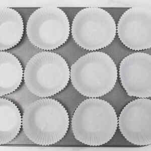 A muffin tin lined with paper liners, ready for baking coffee cake breakfast muffins.