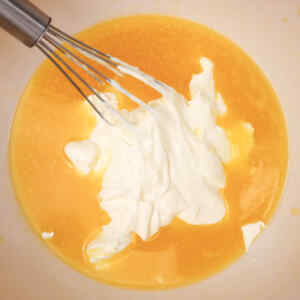 Whisking together creamy ingredients in a bowl for coffee cake muffins.