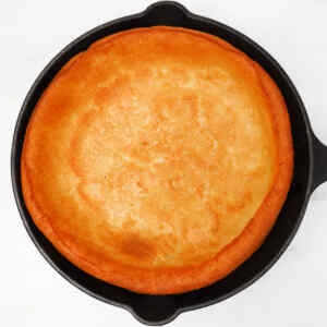 Un panqueque holandés dorado, tipo baby, cocinado en una sartén de hierro fundido.