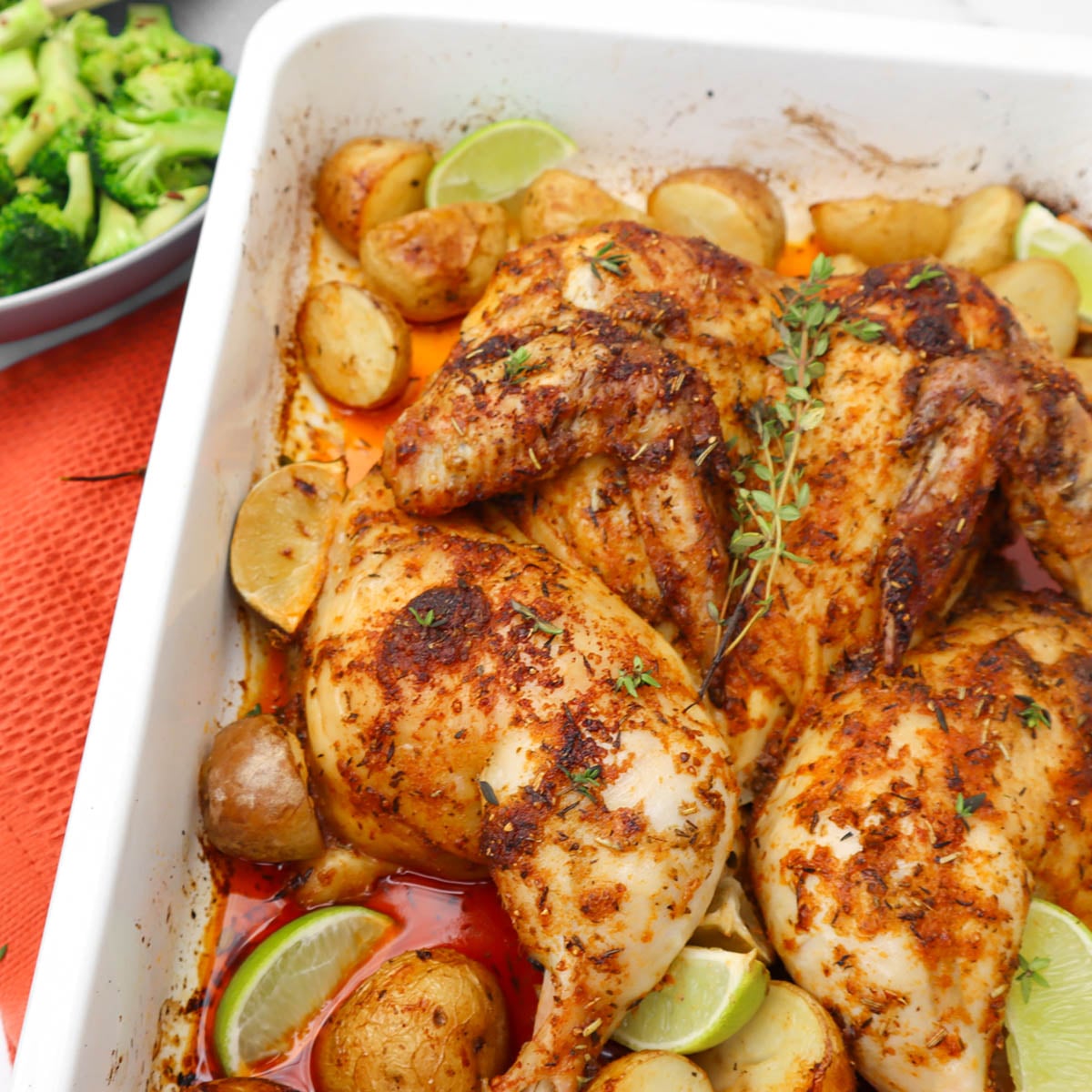 Frango aberto ao estilo mexicano Frango assado no forno, aberto em borboleta, com batatas e limão, guarnecido com ervas.