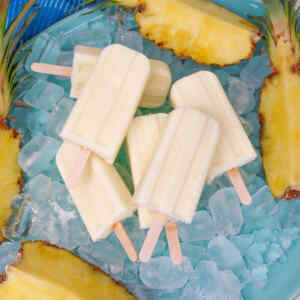 Pineapple popsicles on ice with fresh pineapple slices.