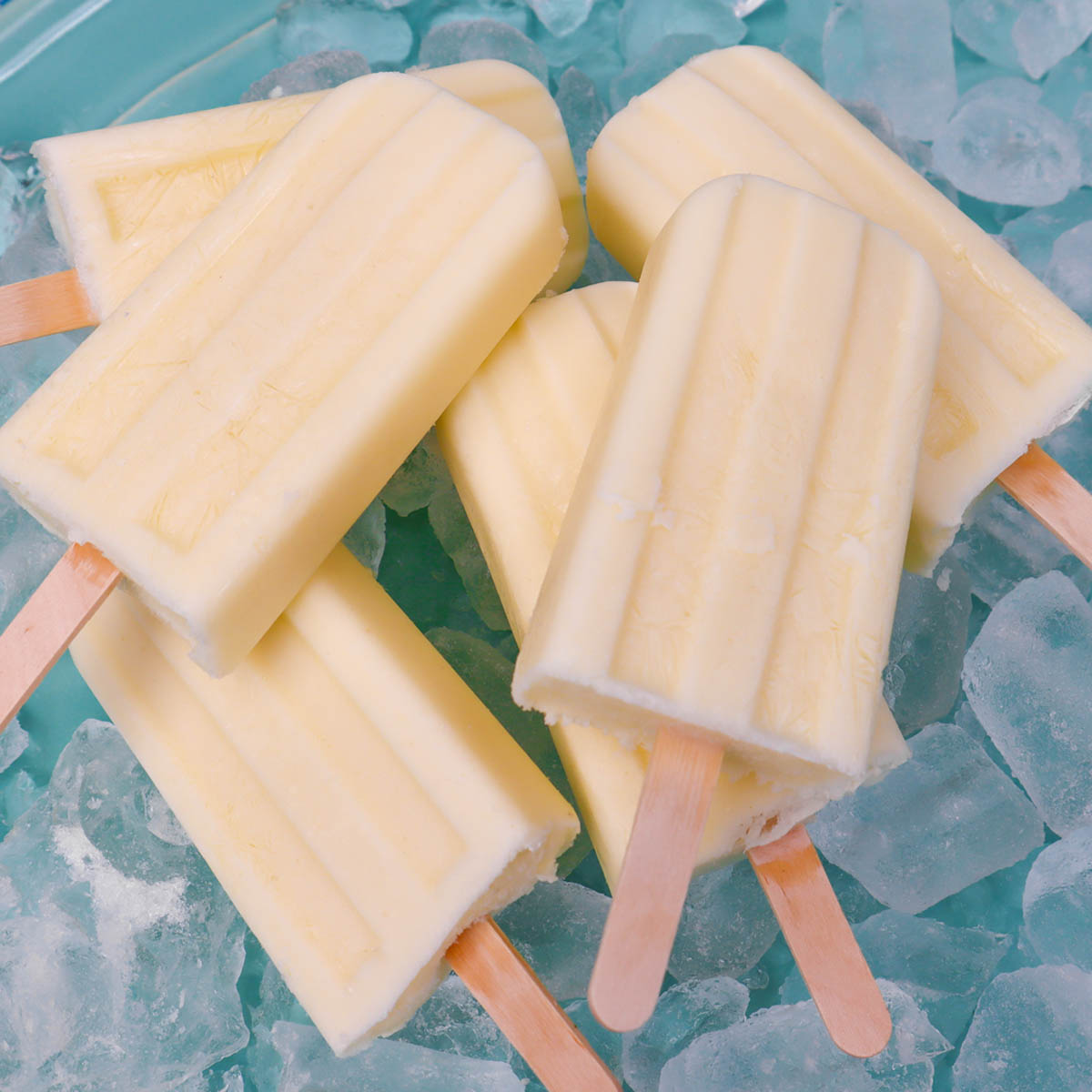 Pineapple Popsicles A close-up of pineapple popsicles resting on ice.