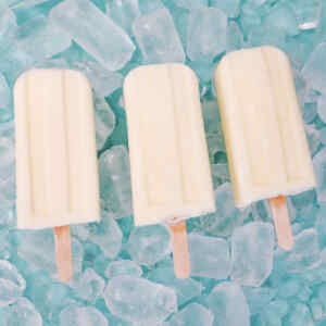 Three pineapple popsicles on a bed of ice cubes.