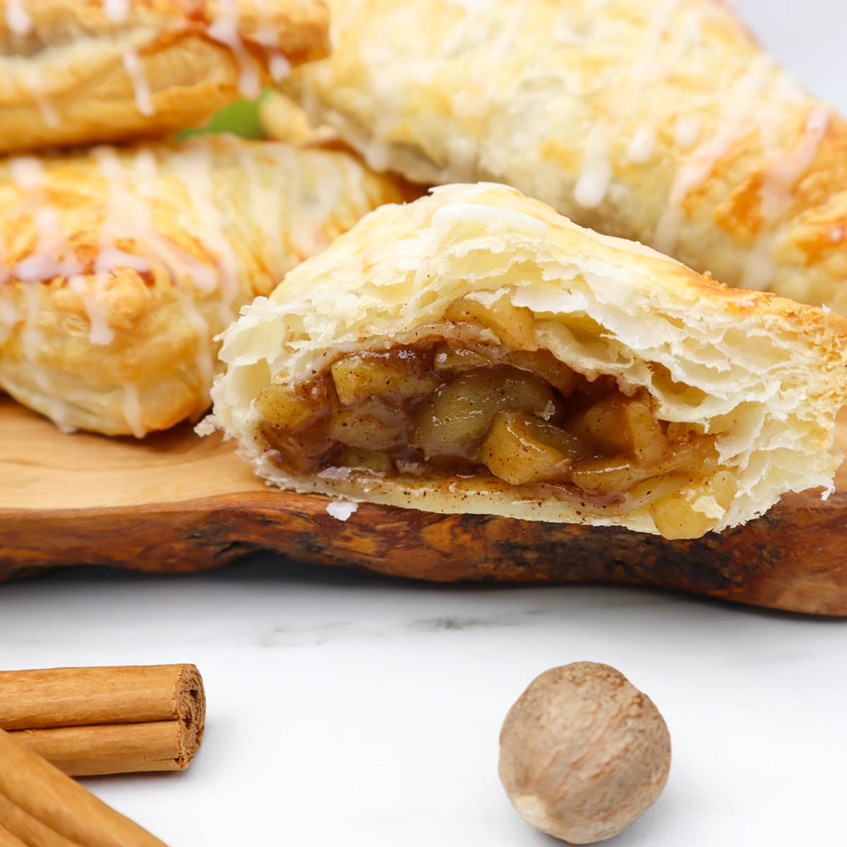 Puff Pastry Apple Turnovers A close-up of a puff pastry apple turnover, revealing spiced apple filling inside.