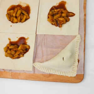 Puff pastry squares with spiced apple filling, one folded into a turnover on the side.