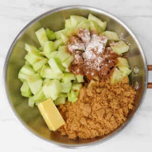 Chopped green apples mixed with brown sugar, butter, and spices in a bowl.