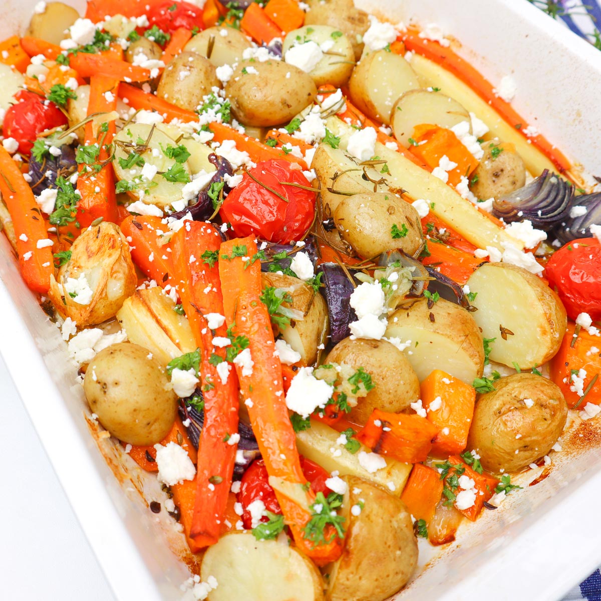 Roasted Vegetable Tray Bake A colorful roasted vegetable tray bake featuring carrots, potatoes, and cherry tomatoes topped with feta cheese.